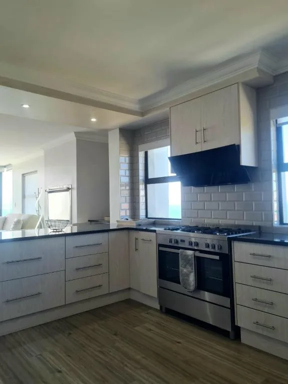 Modern kitchen with stainless steel oven, white cabinetry, dark counters