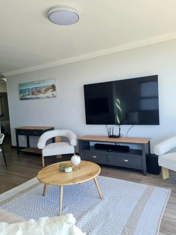 Modern lounge with wall-mounted TV, wooden coffee table, and white armchair