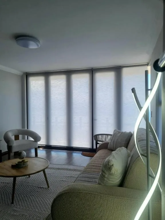 Modern lounge with sofa, armchair, round table, and large windows