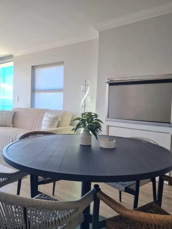 Modern lounge with round black table, sofa, and wall-mounted TV screen