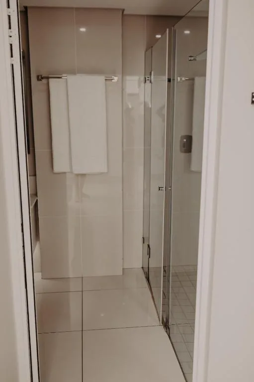 Modern bathroom with large glass shower enclosure and white towel rails