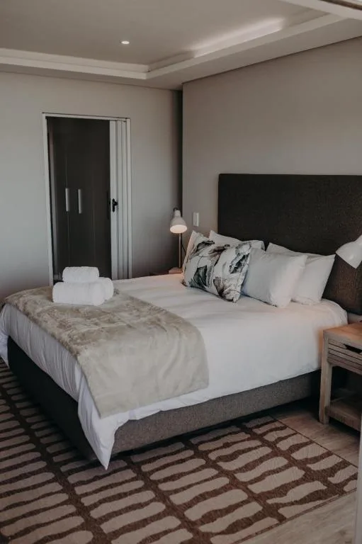 Modern bedroom with black headboard, white bedding, and geometric patterned rug