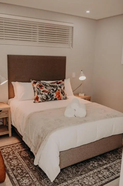 Modern bedroom with brown headboard, white bedding, and decorative pillows