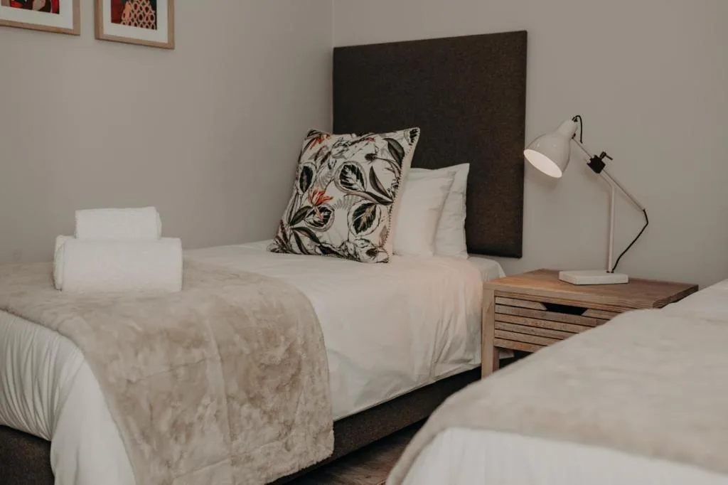 Modern bedroom with twin beds, dark headboard, and contemporary lighting