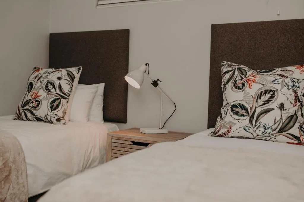 Twin beds with patterned pillows and modern bedside lighting setup