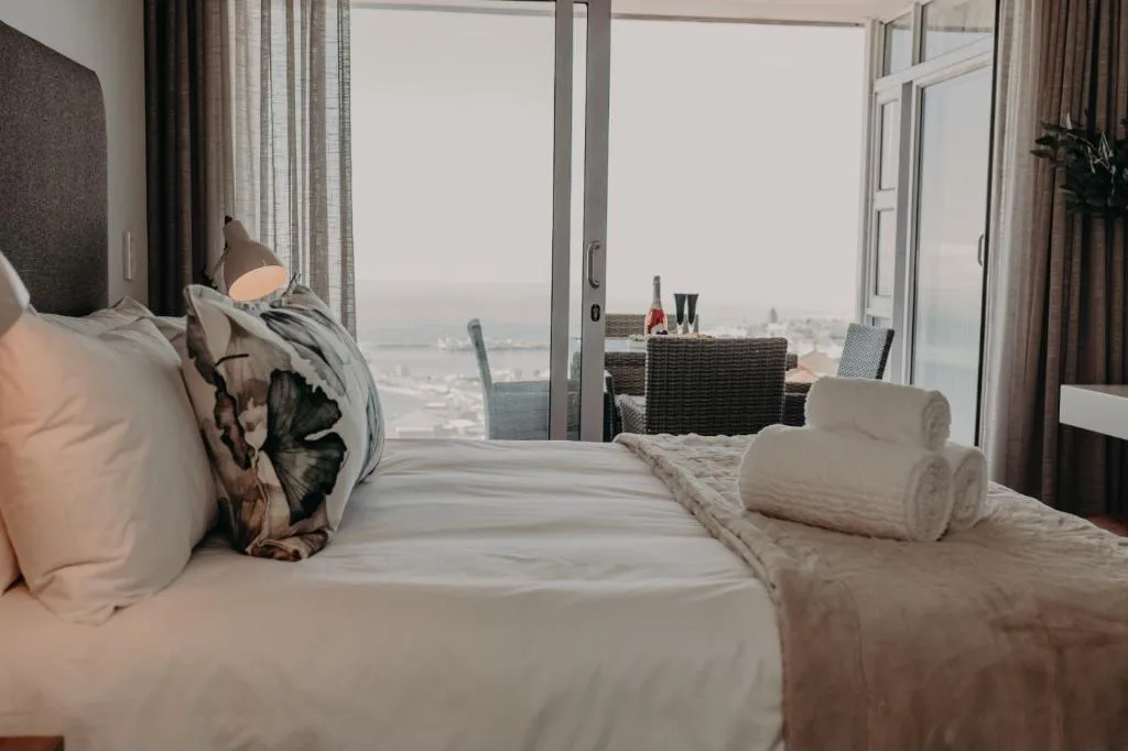 Bedroom with bed, ocean view through large windows, modern furnishings