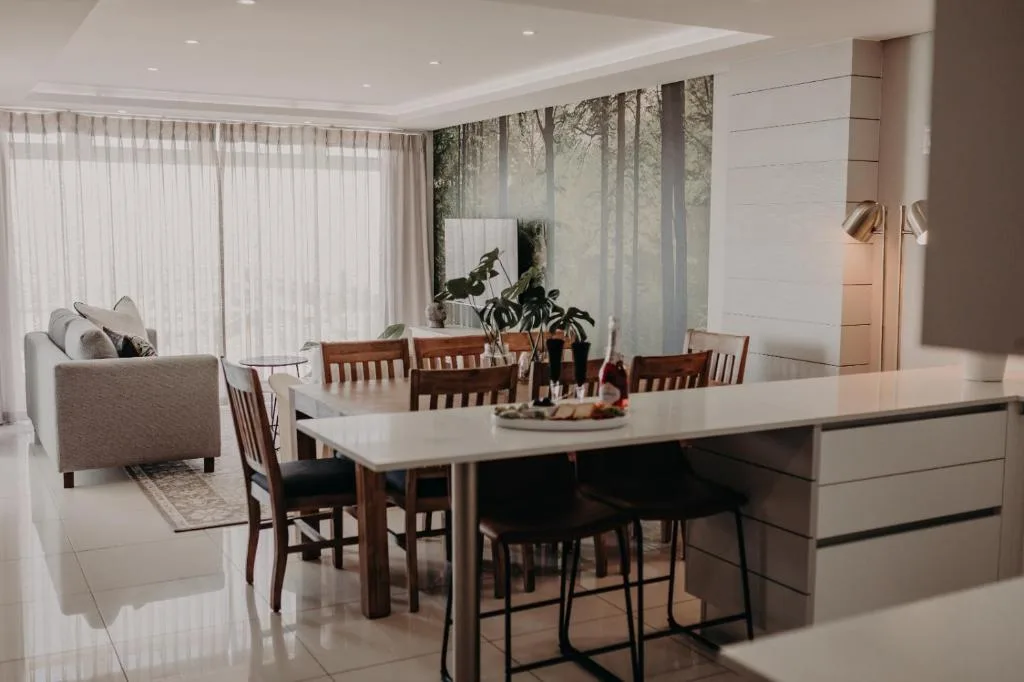 Modern dining area with wooden chairs and white table overlooking lounge