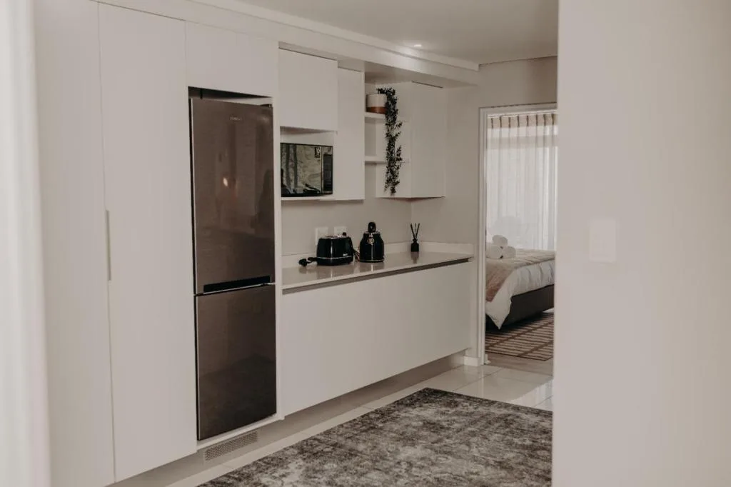 Modern white kitchen with stainless steel refrigerator and open shelving