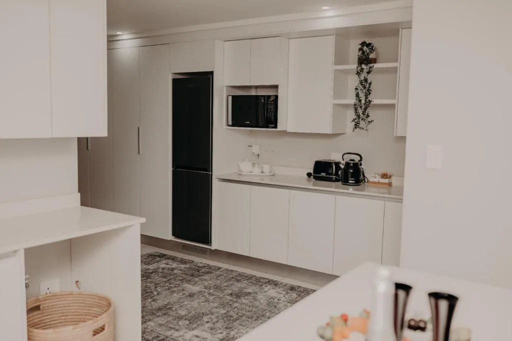 Modern white kitchen with black appliances, microwave, and counter storage