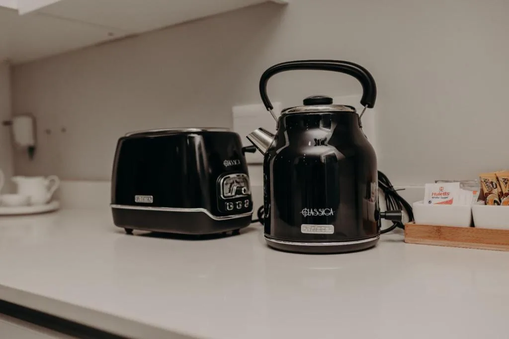Black kettle and toaster on white kitchen counter with amenities