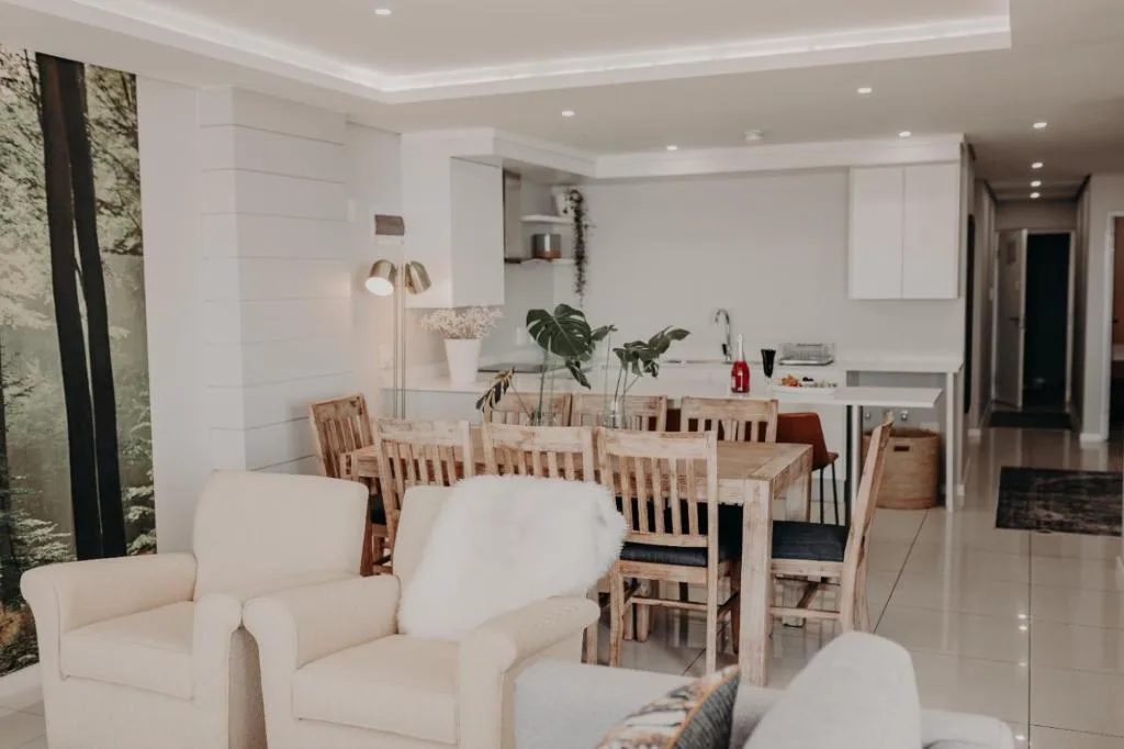 Open-plan lounge with cream armchairs and dining area beyond