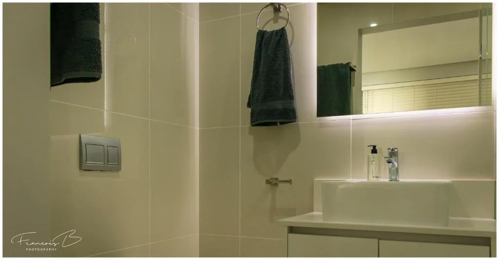 Modern bathroom with wall-mounted vanity, large mirror, and rainfall showerhead