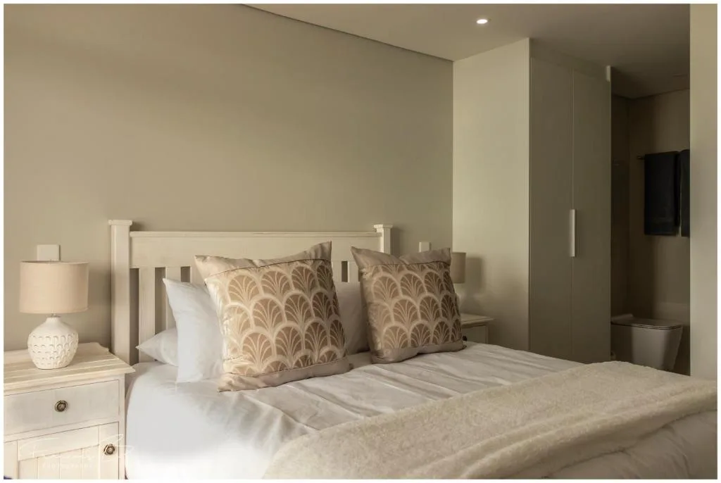 Modern bedroom with white bed, decorative pillows, and neutral tones