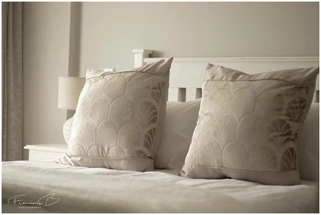 Elegantly styled bed with decorative cushions and neutral bedding in bright light
