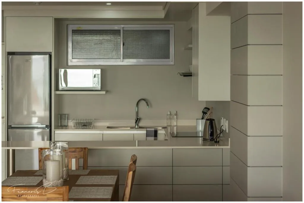 Modern kitchen with stainless steel fridge, sink, and cream cabinetry