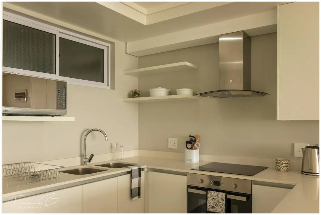 Modern kitchen with cream cabinetry, stainless steel appliances, and open shelving