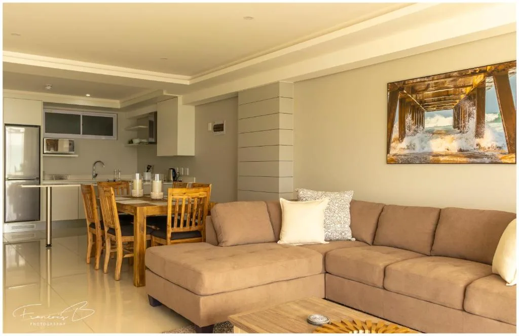 Open-plan lounge with beige sofa, dining table, and modern kitchen