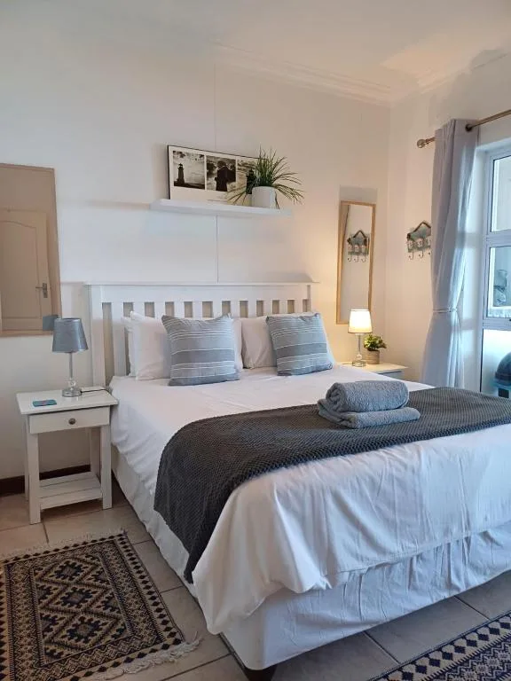 Bright bedroom with white wooden bed, blue striped pillows, bedside lamp