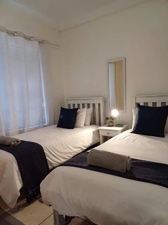 Twin bedroom with white bedding, black accent pillows, and natural light