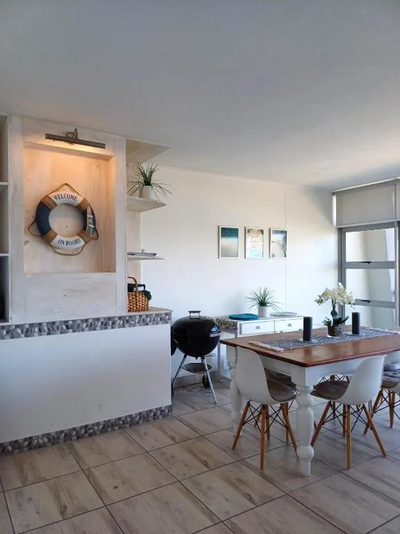 Modern dining area with wooden table, white chairs, and coastal decor