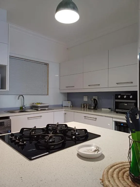 Modern white kitchen with black gas cooktop and stainless steel appliances