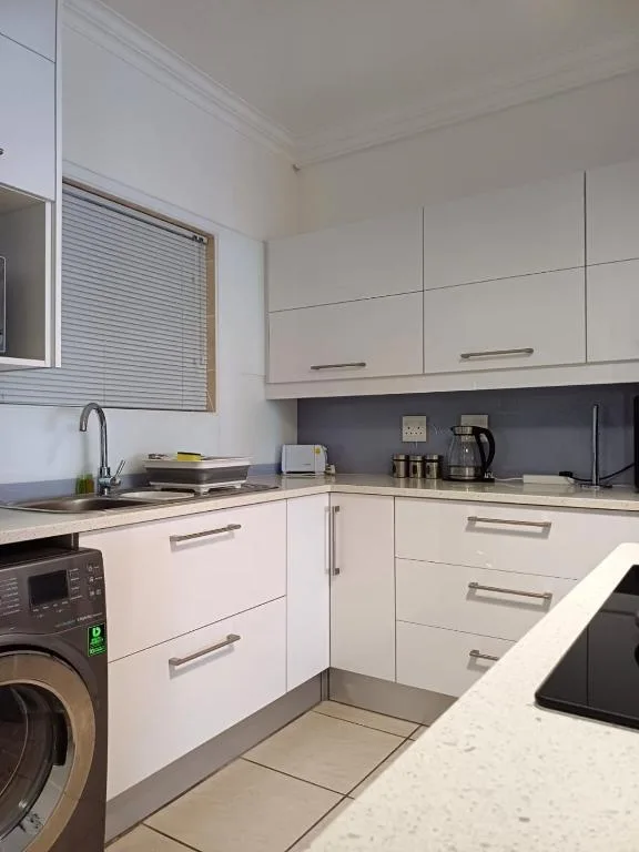 Modern white kitchen with stove, sink, and washing machine appliances