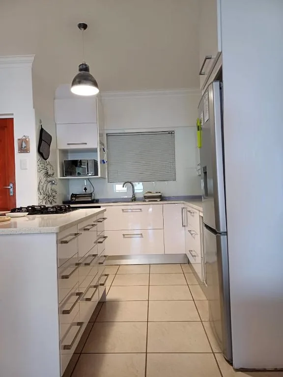 Modern kitchen with white cabinetry, stainless steel appliances, and pendant lighting
