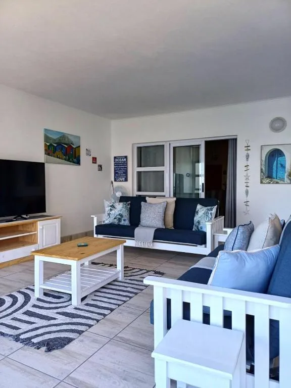 Bright living room with navy sofas, wooden coffee table, and TV entertainment area