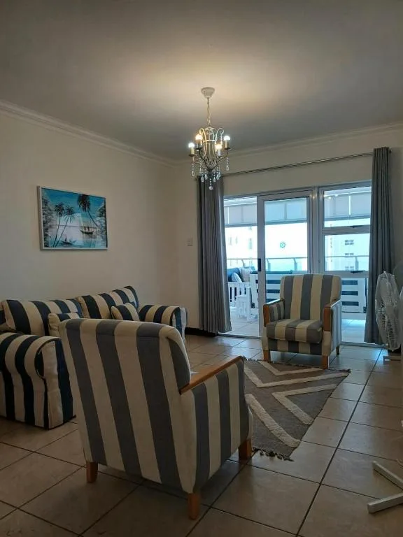Bright lounge with striped armchairs, chandelier, and ocean view doors
