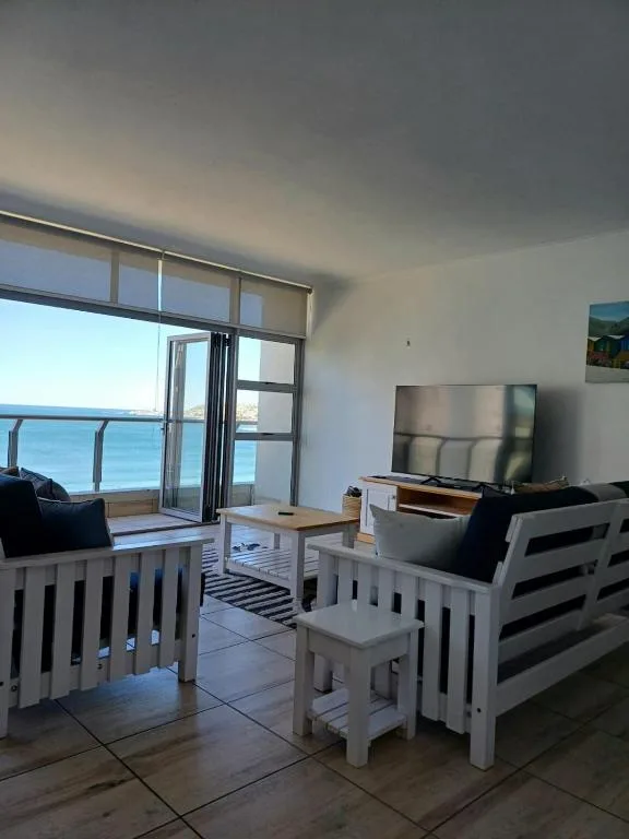 Bright coastal lounge with ocean views through glass doors and deck access