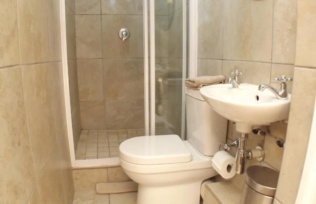 Compact bathroom with shower enclosure, toilet, and wall-mounted sink
