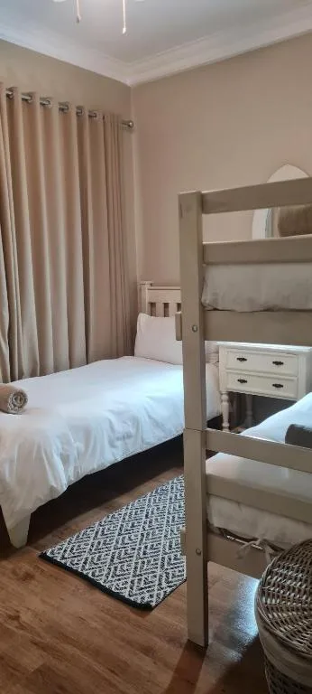 Spacious bedroom with bunk beds, white bedding, and beige curtains