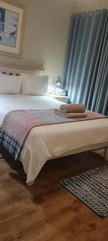 Neatly made bed with white linens and patterned throw blanket in bright bedroom