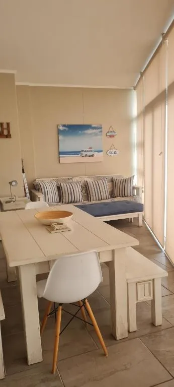 Bright lounge with dining table, striped cushioned seating, coastal artwork