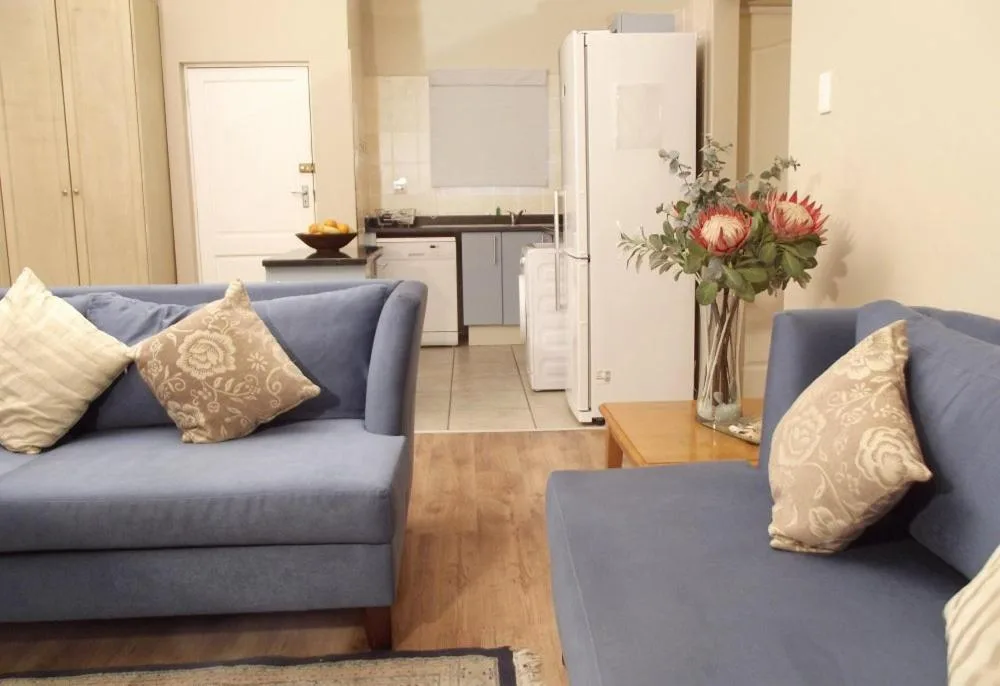 Open-plan lounge with blue sofas and fresh protea flowers arrangement