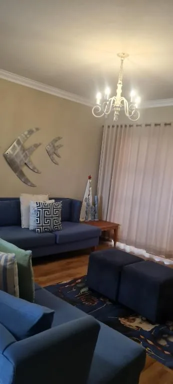 Modern lounge with navy sofas, elegant chandelier, and decorative wall art