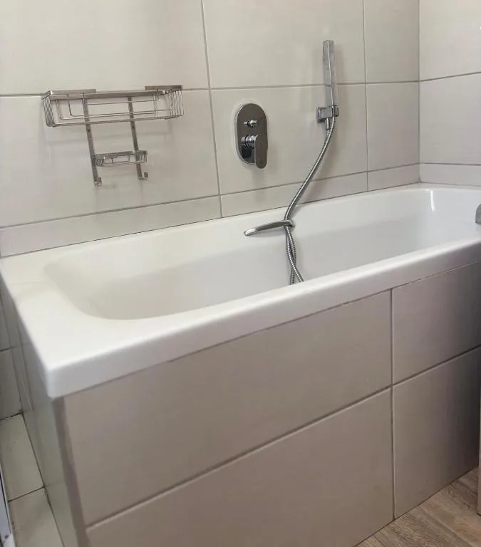 Modern white bathtub with chrome fixtures and tile surround