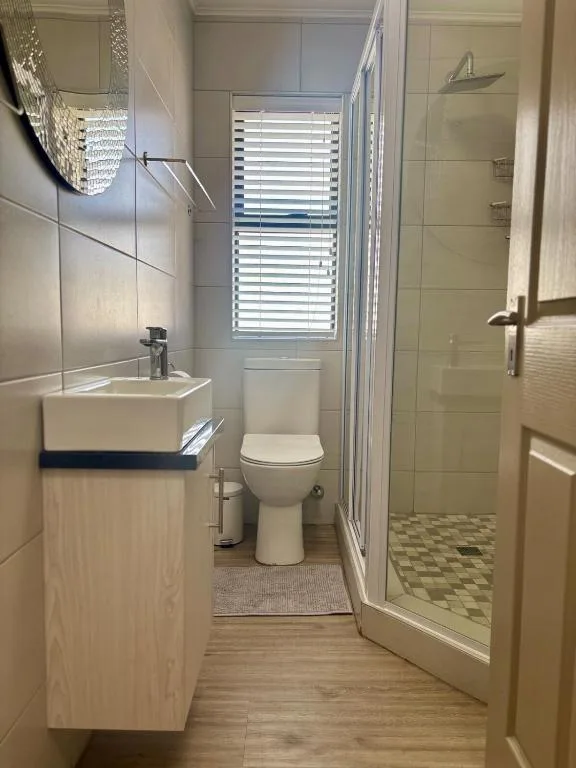 Modern bathroom with shower enclosure, toilet, and white vanity sink