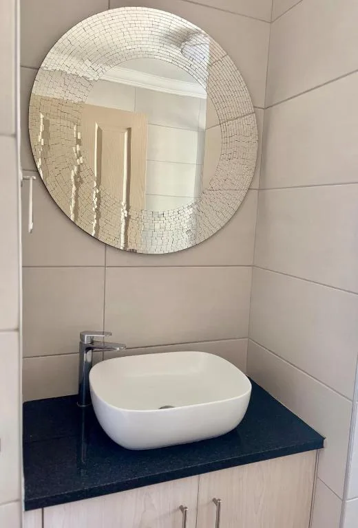 Modern bathroom vanity with white bowl sink and circular mirror