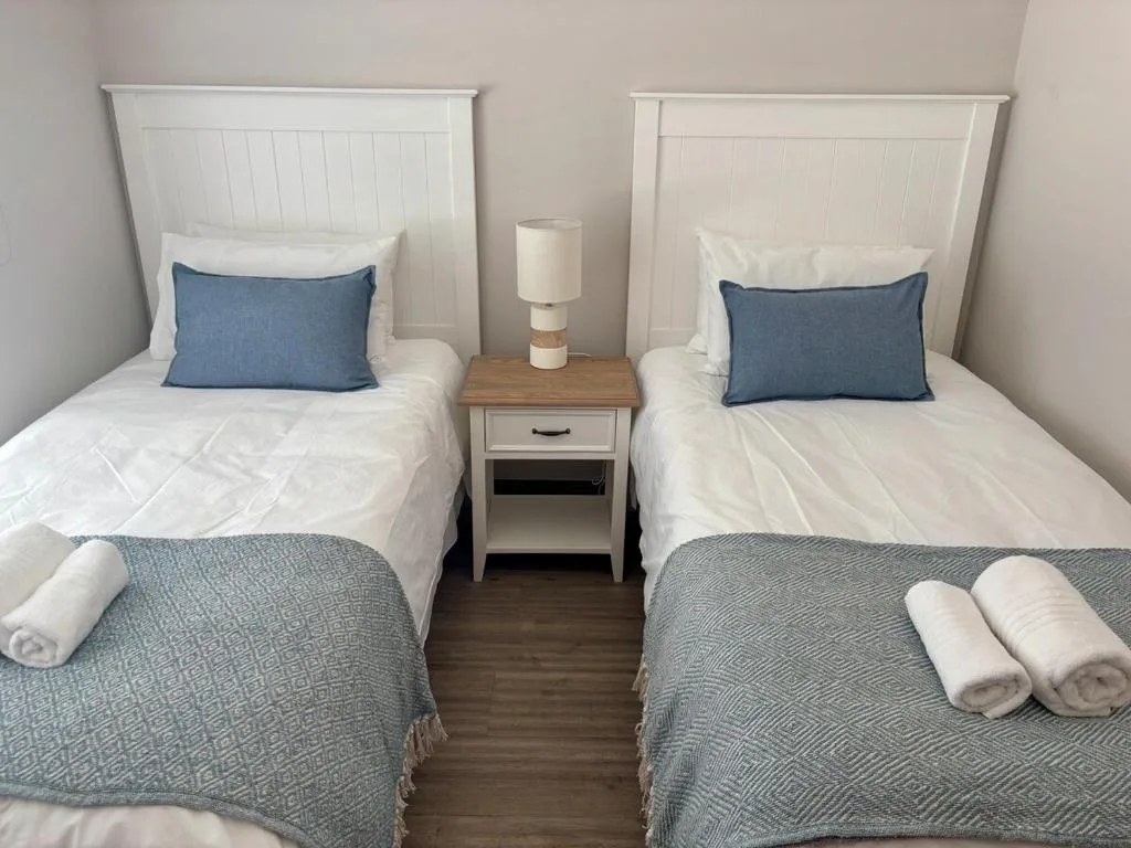 Twin bedroom with white headboards, blue pillows, and gray throws