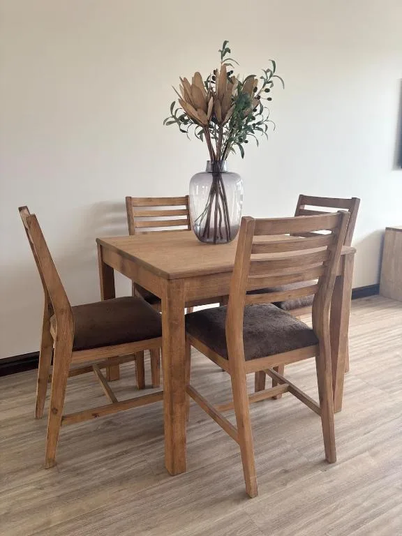 Wooden dining table with four chairs and dried flower arrangement centerpiece