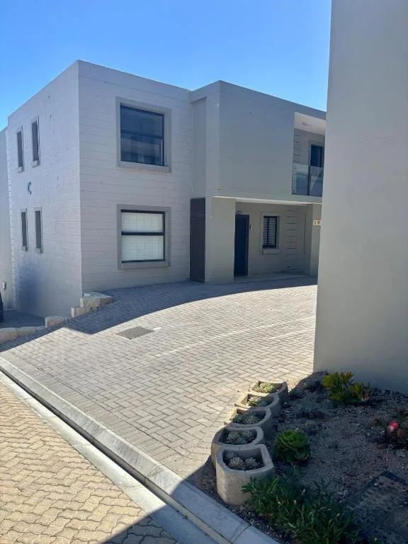 Modern white two-story apartment building with paved driveway and landscaping