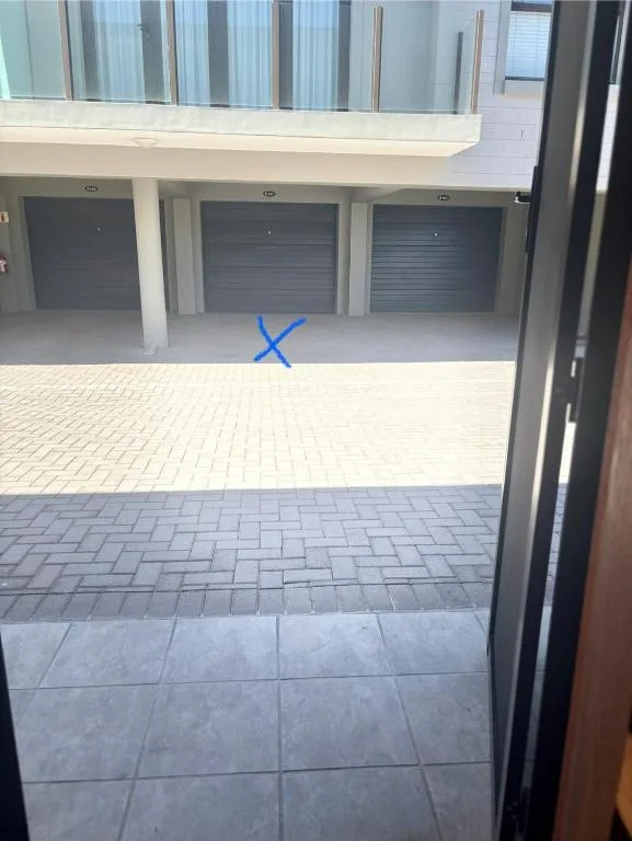 Modern apartment building entrance with three garage doors and paved courtyard