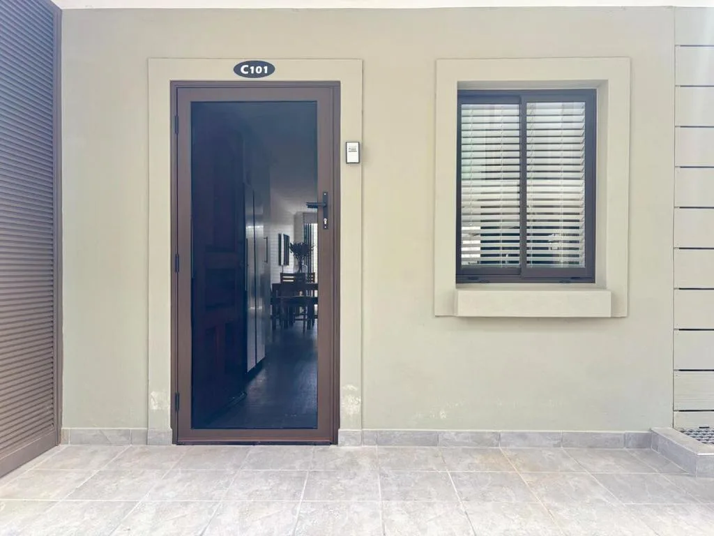 Modern apartment entrance with dark door and shuttered window, unit C101
