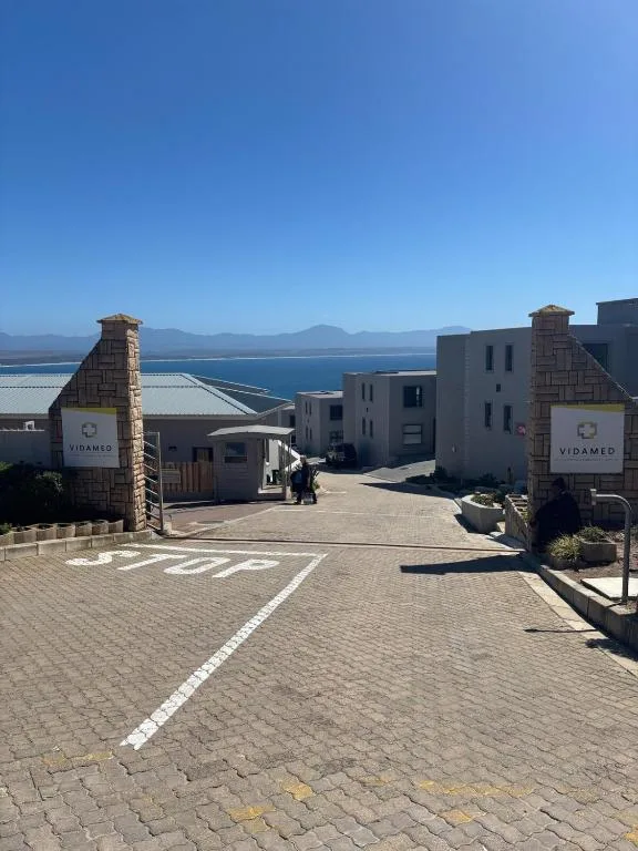Modern apartment complex entrance with bay views and mountains in distance