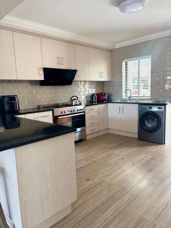 Modern kitchen with white cabinetry, black countertops, and stainless steel appliances