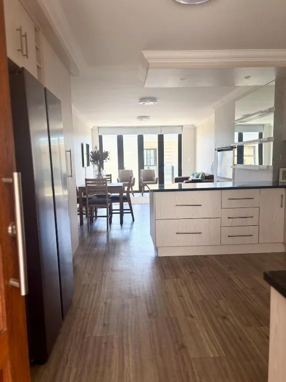 Modern kitchen with white cabinetry opening to dining and lounge areas