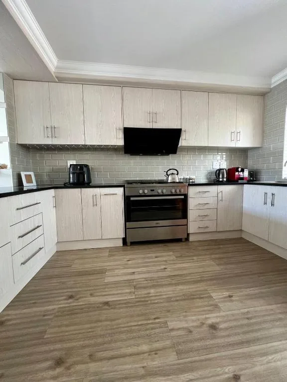 Modern kitchen with light wood cabinetry, black stove, and grey subway tile backsplash