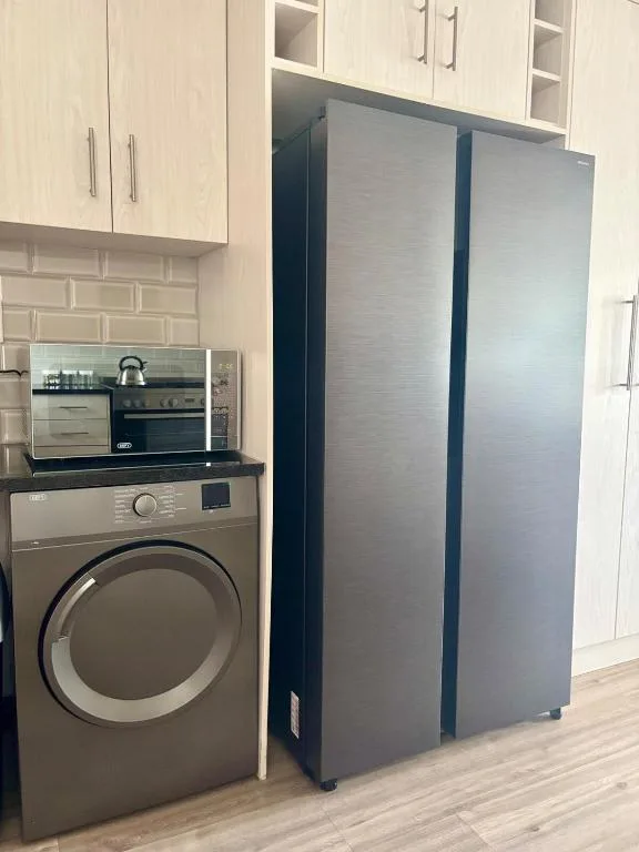 Modern kitchen with stainless steel appliances, washing machine, and cream cabinetry