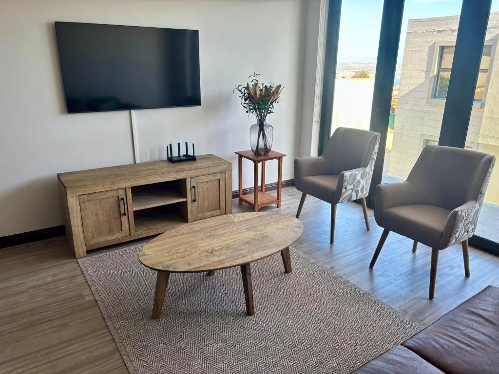 Modern lounge with TV, wooden furniture, and comfortable seating chairs